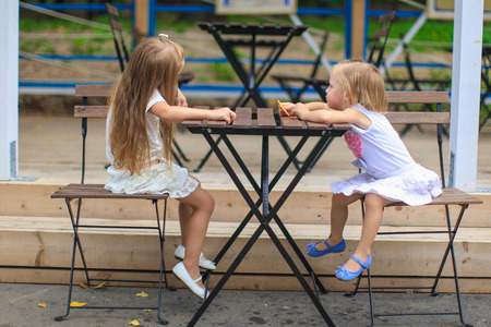 Little adorable girls at outdoor cafe on warm dayの写真素材