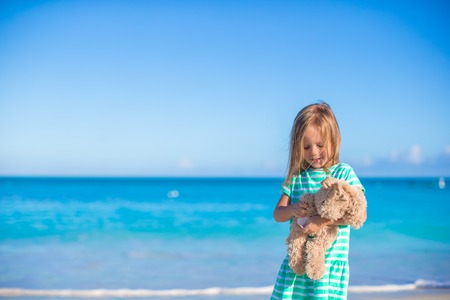 Adorable little girl with her toy on tropical beach vacationの写真素材