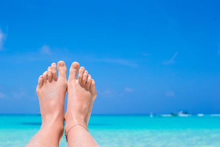 Close up of female feet on white sandy beach