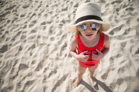 Happy little girl in hat on beach during summer vacationの写真素材