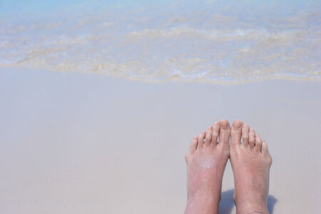 Close up of female feet on white sand beach