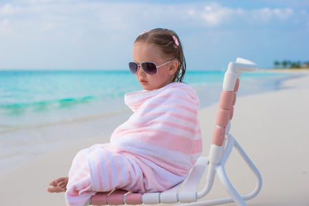 Adorable little girl in sunglasses covered with towelの写真素材