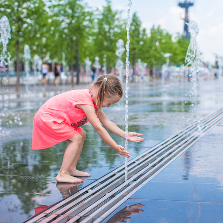 Adorable little girl playing in street fountainの写真素材