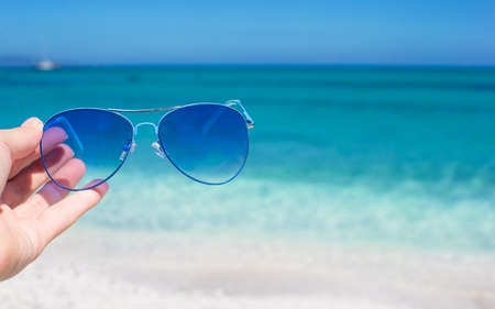 Close up of colorful blue sunglasses on tropical beachの写真素材
