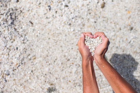 Hands in the form of heart with pebbles insideの写真素材