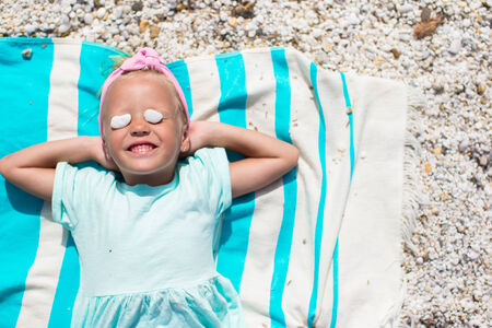 Adorable little girl have fun on towel at white beach