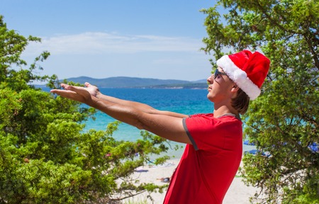 Young man in Santa Hat on tropical beach near the firsの写真素材