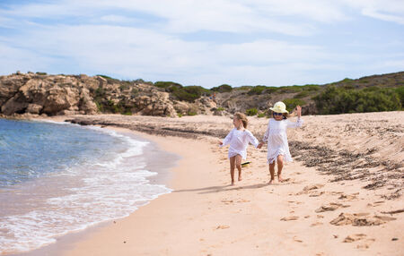Adorable cute girls have fun on white beach during vacationの写真素材