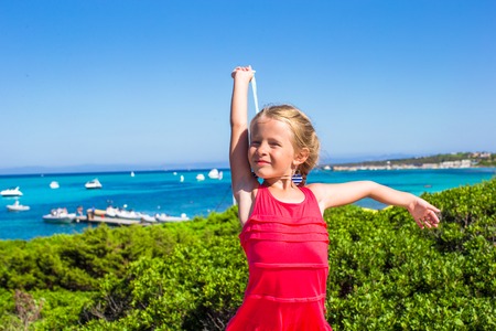 Little adorable girl enjoying beautiful view of turquoise sea on the island of Sardiniaの写真素材