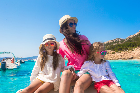 Young mother with her adorable daughters resting on a big boatの写真素材