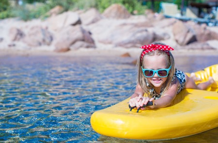 Little cute girl enjoying swimming on yellow kayak in the clear turquoise waterの写真素材