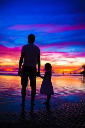 Father and daughter silhouette in the sunset on the beach on Boracayの写真素材