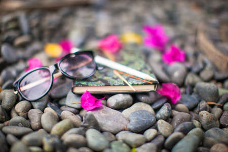 Notepads plans and sunglasses on a gravel road to the seaの写真素材