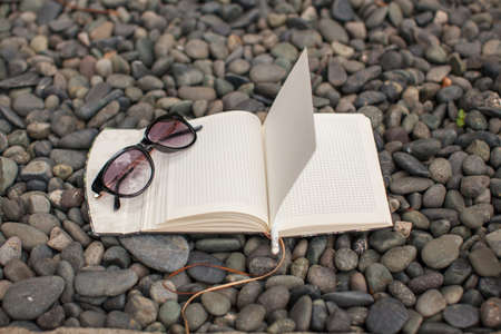 Notepads plans and sunglasses on a gravel road to the seaの写真素材