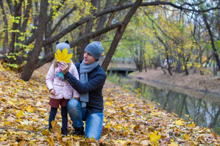 Little girl and happy dad in autumn park outdoorsの写真素材