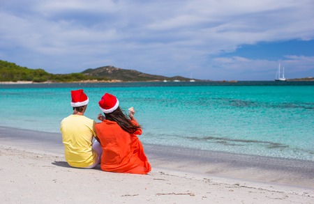 Young romantic couple in Santa hats during beach vacationの写真素材
