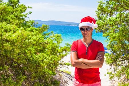 Young man in red christmas Hat on tropical beach near the firsの写真素材