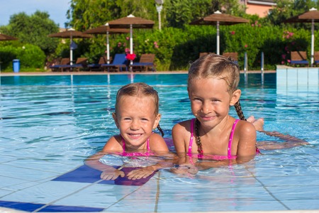 Adorable happy little girls having fun in the swimming poolの写真素材