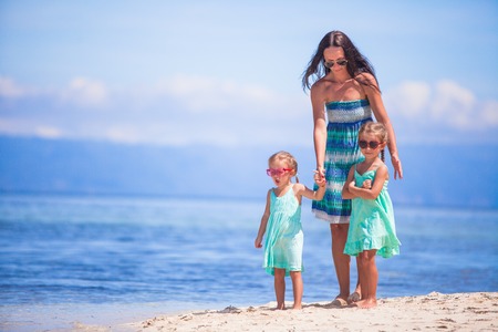 Adorable little girls and young mother on tropical white beach in desert islandの写真素材