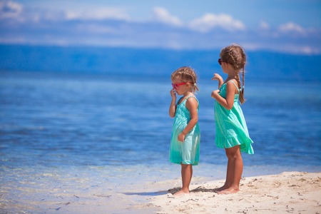 Little adorable girls on white beach look at the seaの写真素材