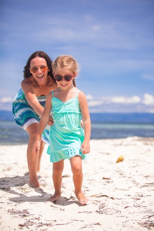 Little girl and young mother having fun on tropical beachの写真素材