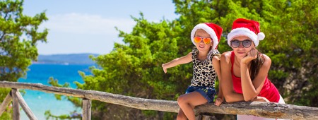 Young mother and little girl in red Christmas hat at tropical beachの写真素材