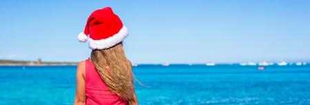 Cute little girl in Santa hat on the beach during vacationの写真素材