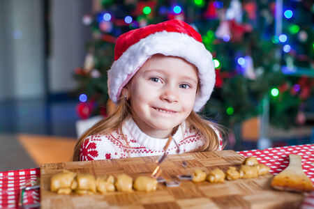 Adorable little girl baking gingerbread cookies for Christmas