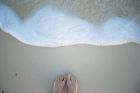Women's beautiful legs on white sandy beach