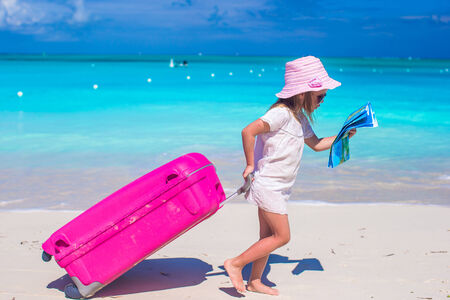 Little adorable girl with big suitcase on tropical vacationの写真素材