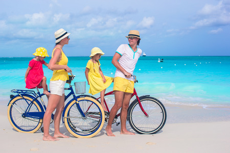 Young happy family riding bicycles on tropical beachの写真素材