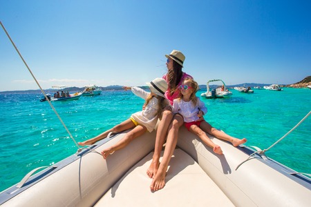 Young mother with her adorable little girls resting on a big boatの写真素材