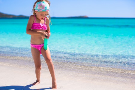 Little adorable girl in swimsuit with suntan lotion bottleの写真素材