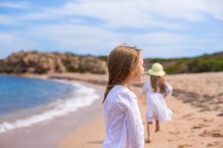 Adorable cute girls have fun on white beach during vacationの写真素材