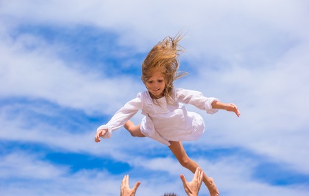 Adorable little girl and happy father have fun on beachの写真素材