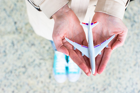 Closeup hand holding an airplane model at airportの写真素材