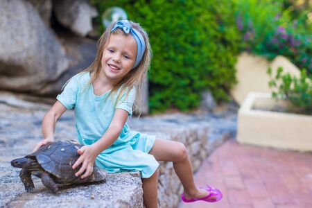 Little adorble happy girl with small turtle outdoorsの写真素材