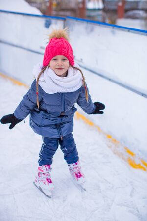 Adorable little girl skating on the ice-rink