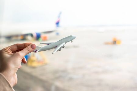 Close up hand holding an airplane model at airportの写真素材