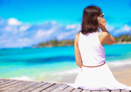 Young woman talking on phone during tropical beach vacationの写真素材