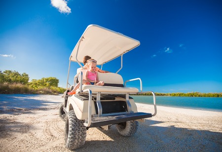 Little girl with father golf cart on tropical beachの写真素材