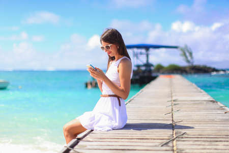 Young woman talking on phone during tropical beach vacationの写真素材
