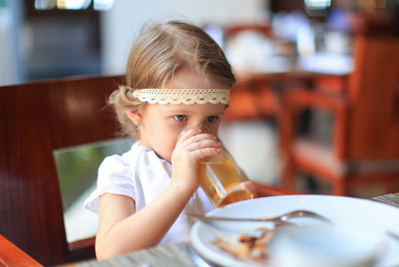 Adorable little girl having breakfast at restaurantの写真素材