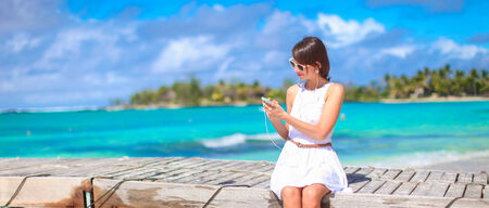 Young woman talking on phone during tropical beach vacationの写真素材