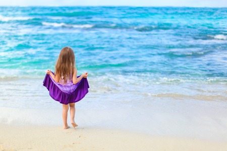 Little girl having fun on tropical beach with turquoise ocean waterの写真素材