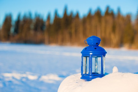 Blue lantern with a candle on white snow outdoor