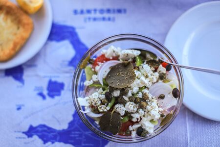 Greek salad on the table with map of Santorini, Greece