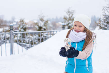 Adorable little girl holding Christmas lantern outdoors on beautiful winter snow dayの写真素材