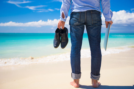 Young man with laptop on the background of turquoise ocean at tropical beachの写真素材