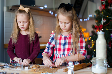 Little girls baking gingerbread cookies for Christmas at home kitchenの写真素材